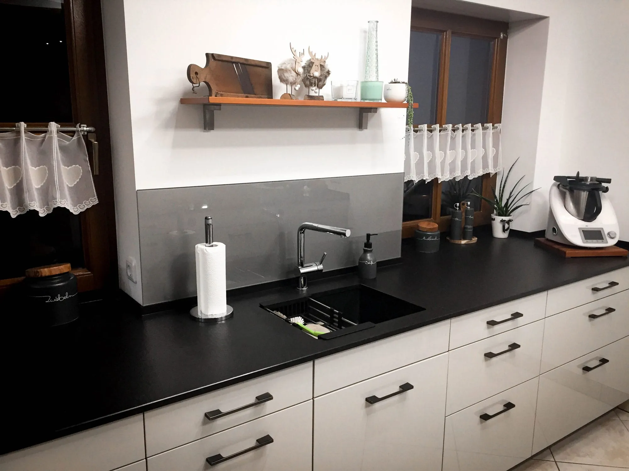 Kundenprojekt: Küchenzeile in Creme-Hochglanz mit grauer Glas-Rückwand und Holz-Wandregal