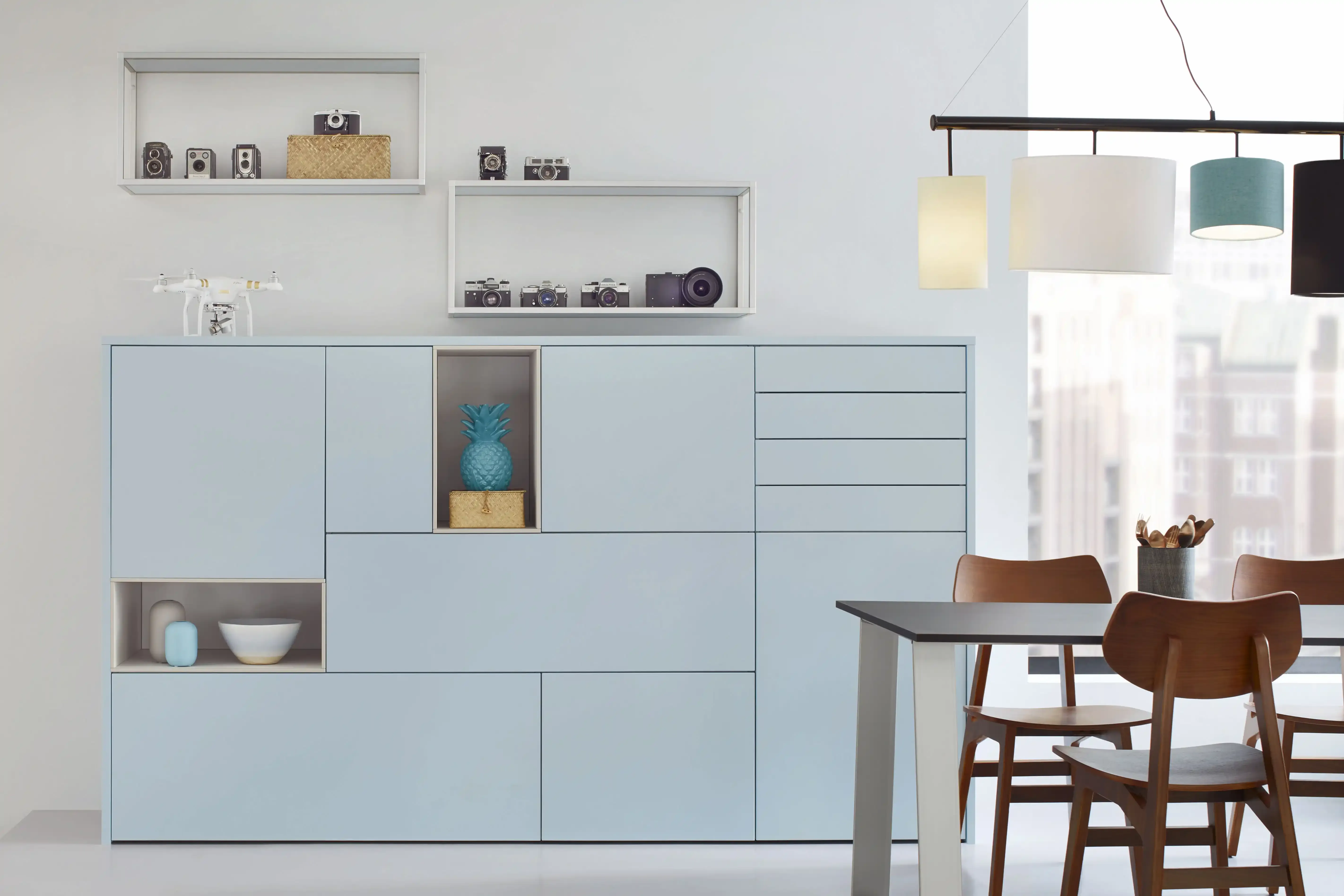 Pastellblaue Sideboard-Wand mit offenen Nischen, Vintage-Deko und Essbereich mit Hängeleuchten