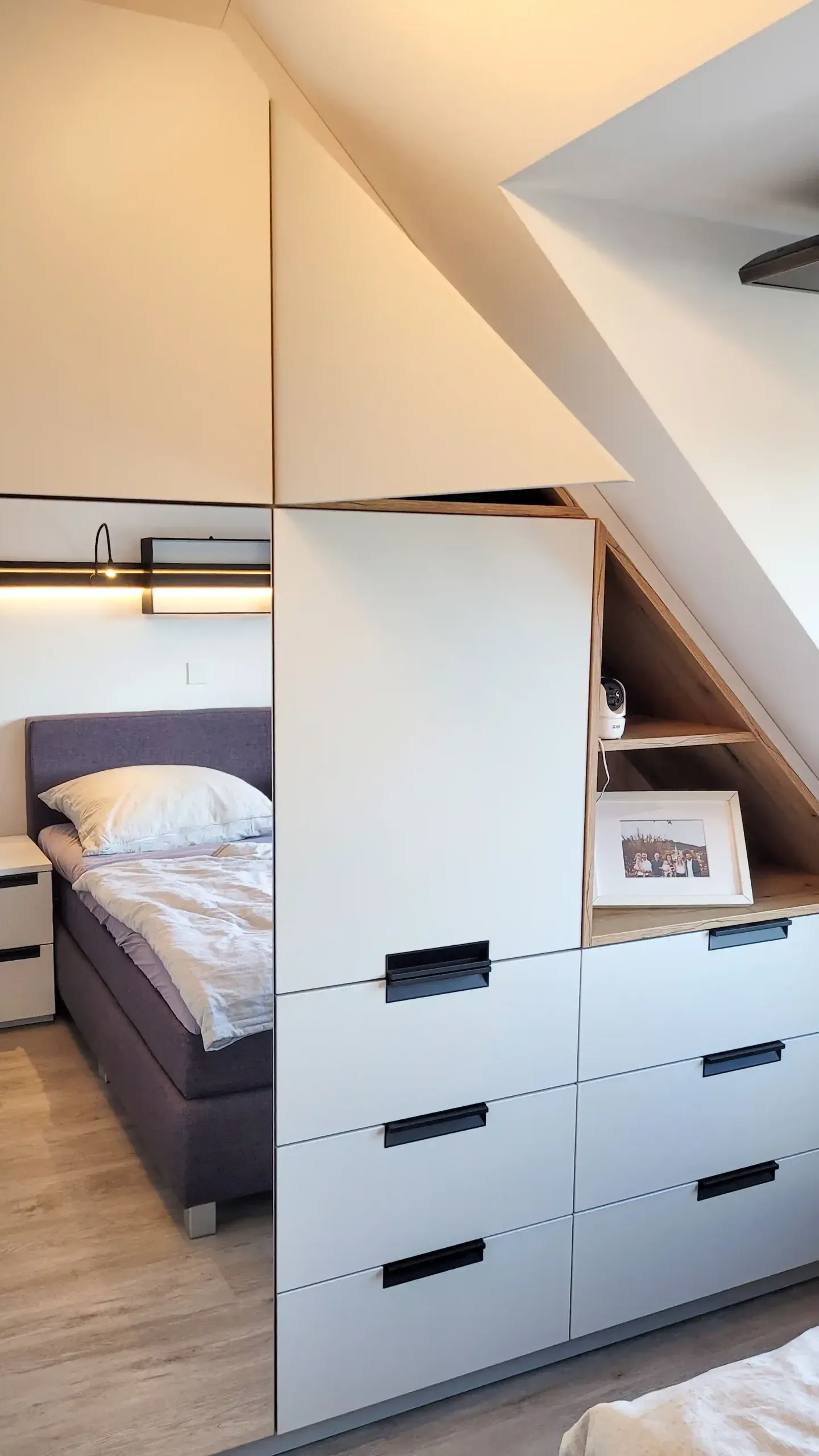 Maßgefertigter Einbauschrank unter Dachschräge mit sechs Schubladen und offener Bilder-Nische.