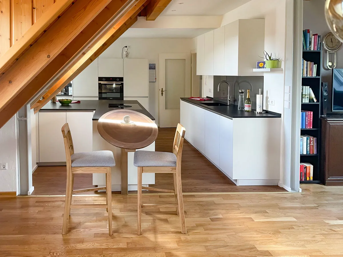 Dachgeschoss-Wohnküche mit Massivholz-Esstheke, Holzhockern und Küchenzeile