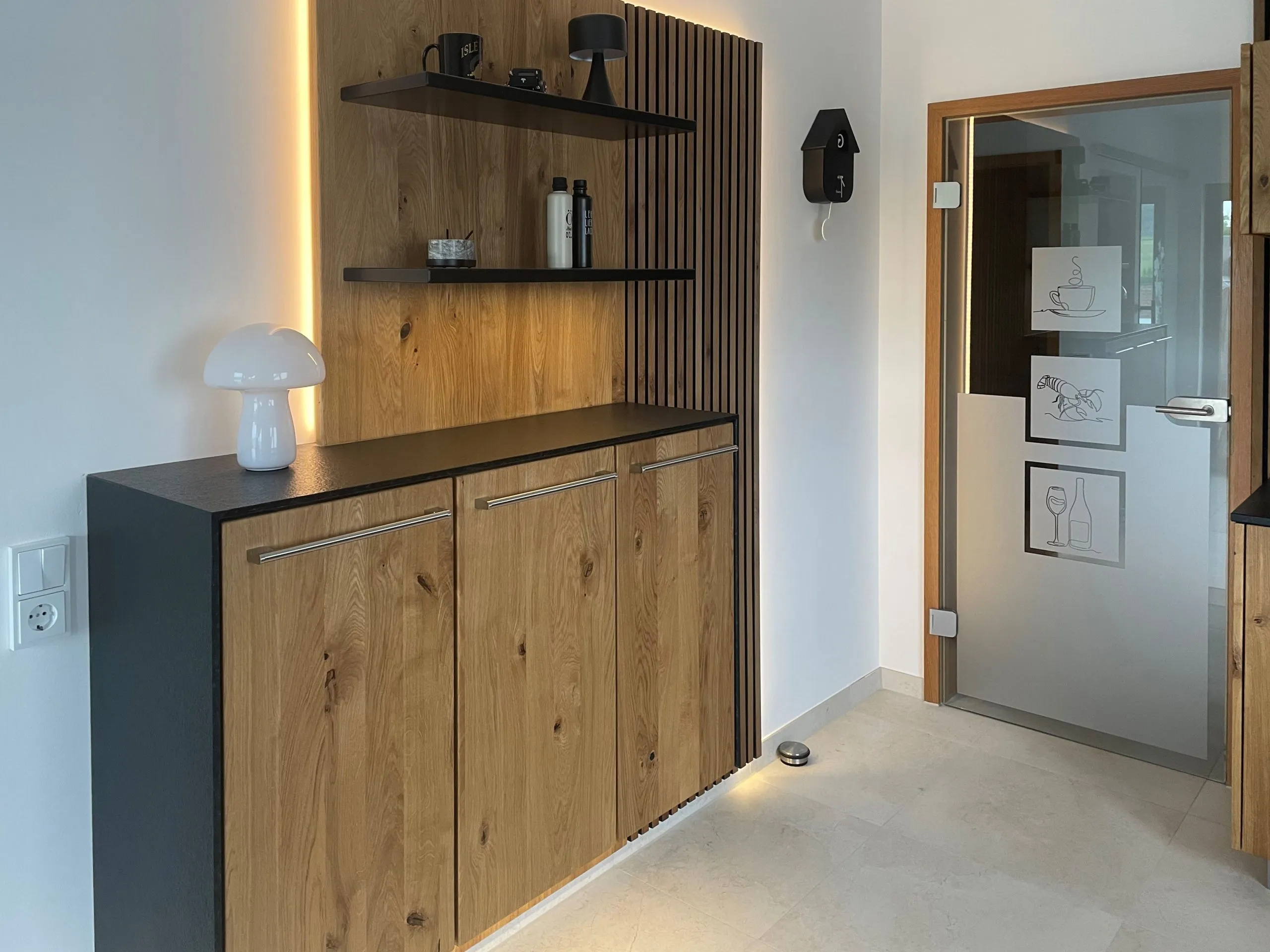 Sideboard mit Holzfront vor Lamellenwand mit Wandregal, Pilzleuchte und Kuckucksuhr