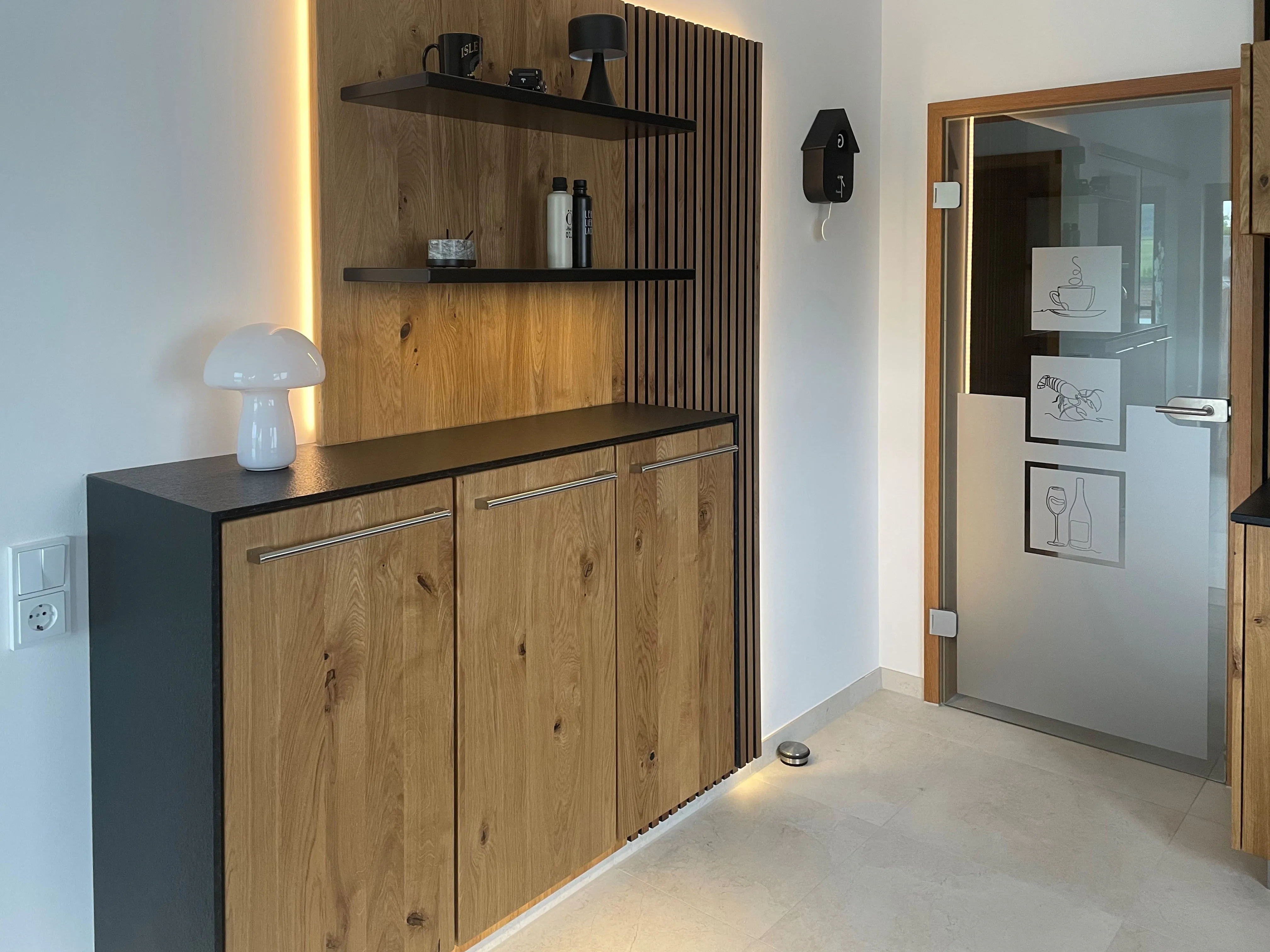 Sideboard mit Holzfront vor Lamellenwand mit Wandregal, Pilzleuchte und Kuckucksuhr