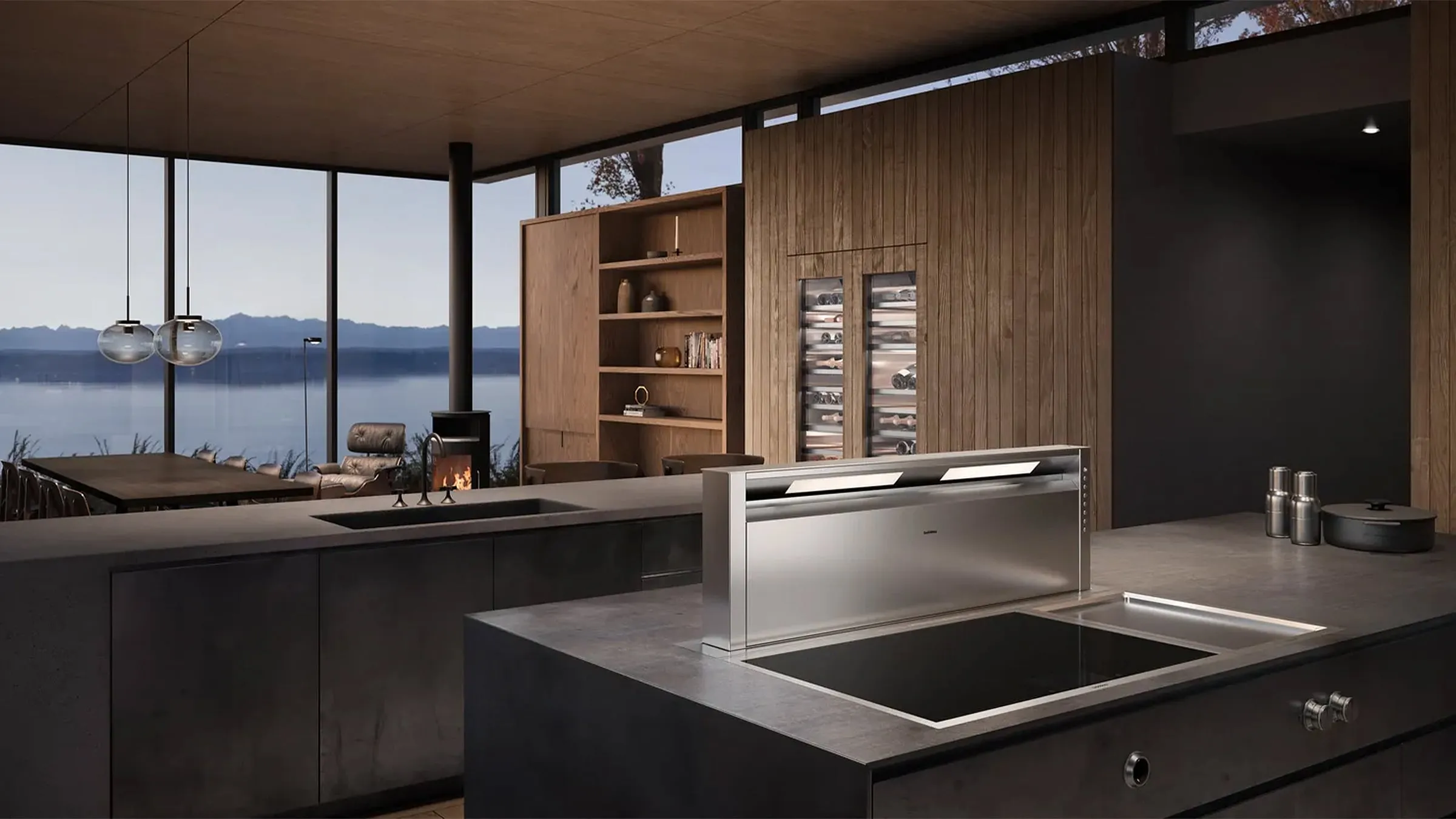 Designküche mit Kochinsel, versenkbarer Gaggenau-Tischlüftung, Induktionskochfeld und Weinklimaschrank vor Seeblick.