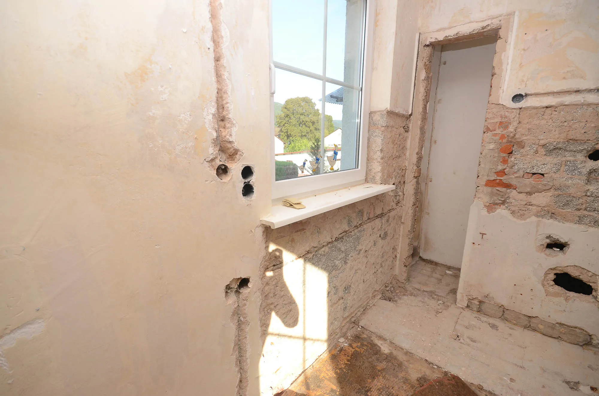 Fensternische im Rohzustand vor der Küchenrenovierung mit freigelegten Wänden und neuer Fensterbank