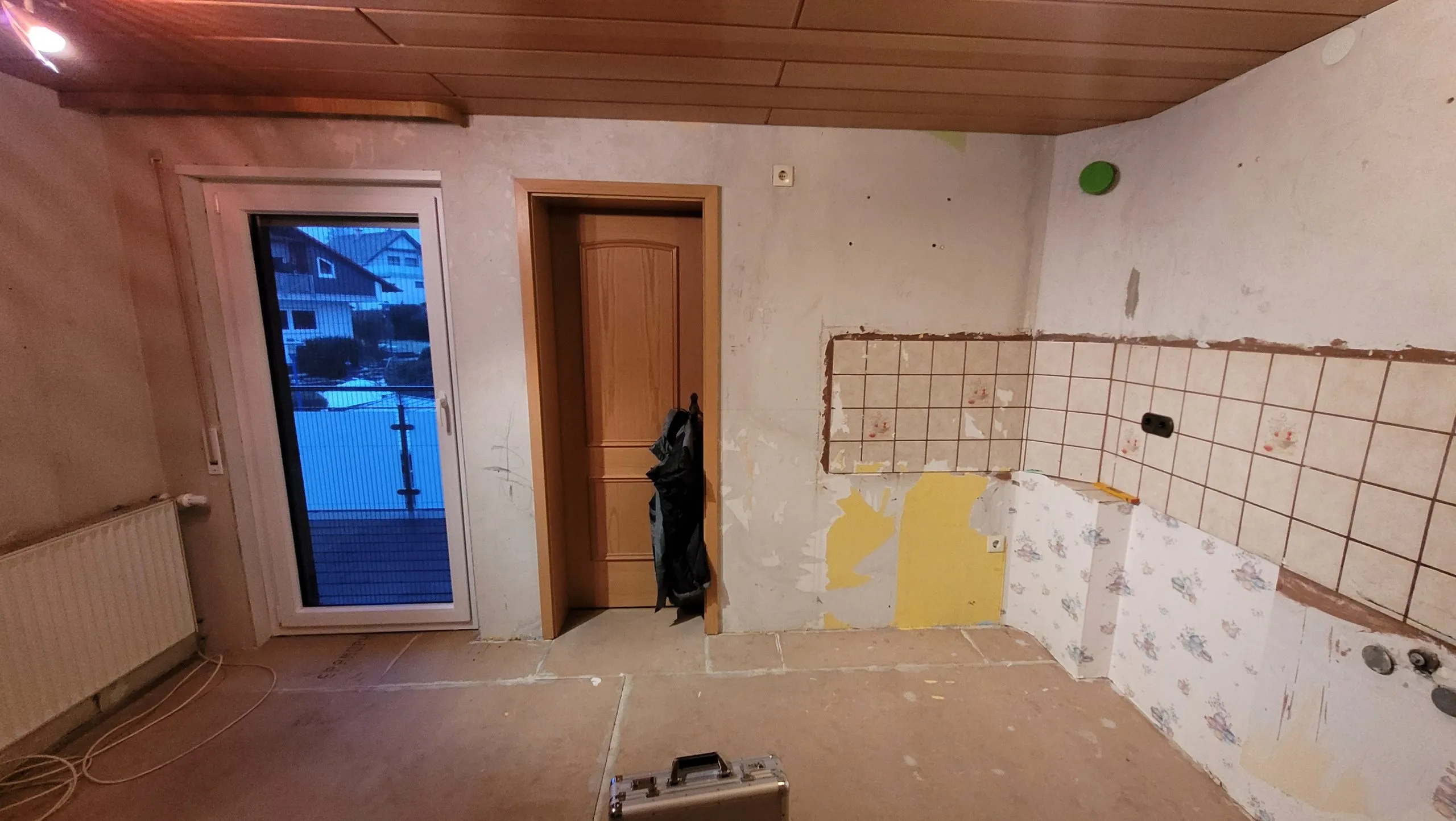 Leerer Raum vor dem Kücheneinbau mit Fenster, Heizkörper und alter Fliesenkante
