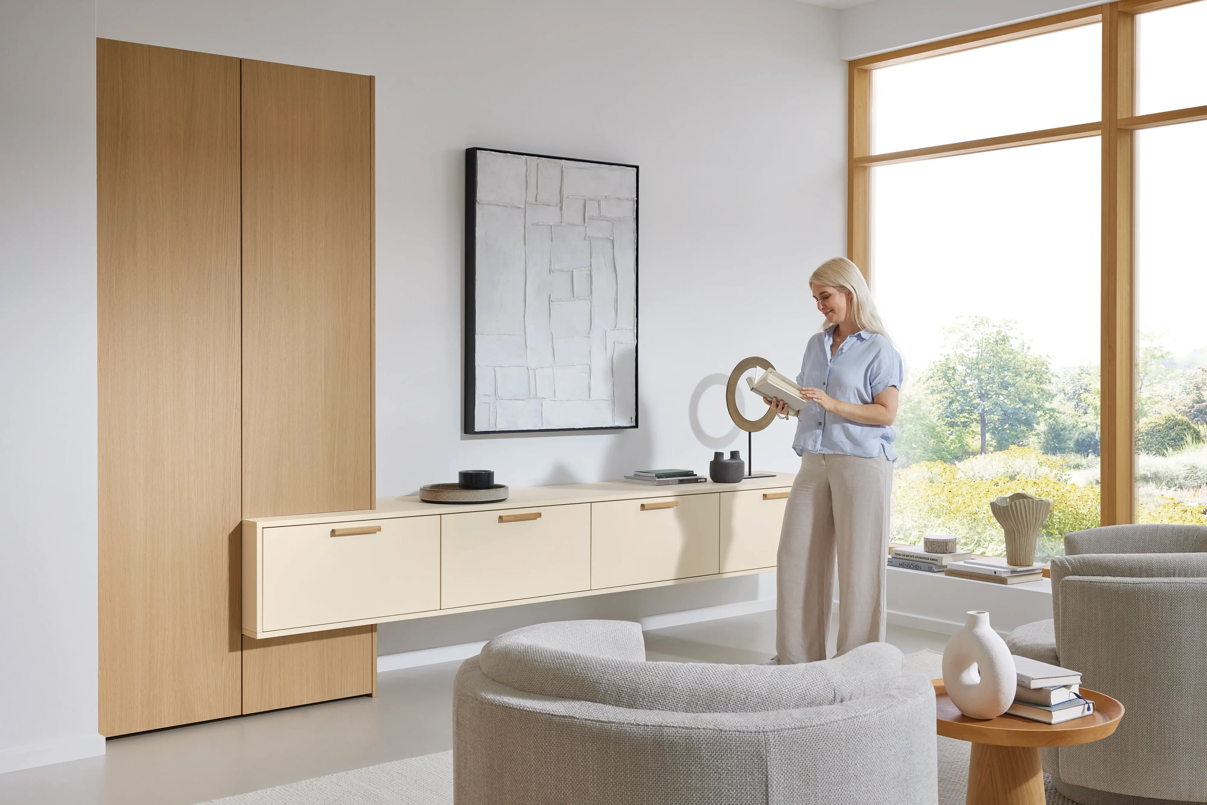 Wohnliche Stauraum-Wand in Eiche und Crème mit Hochschrank, schwebendem Sideboard und Frau mit Vase
