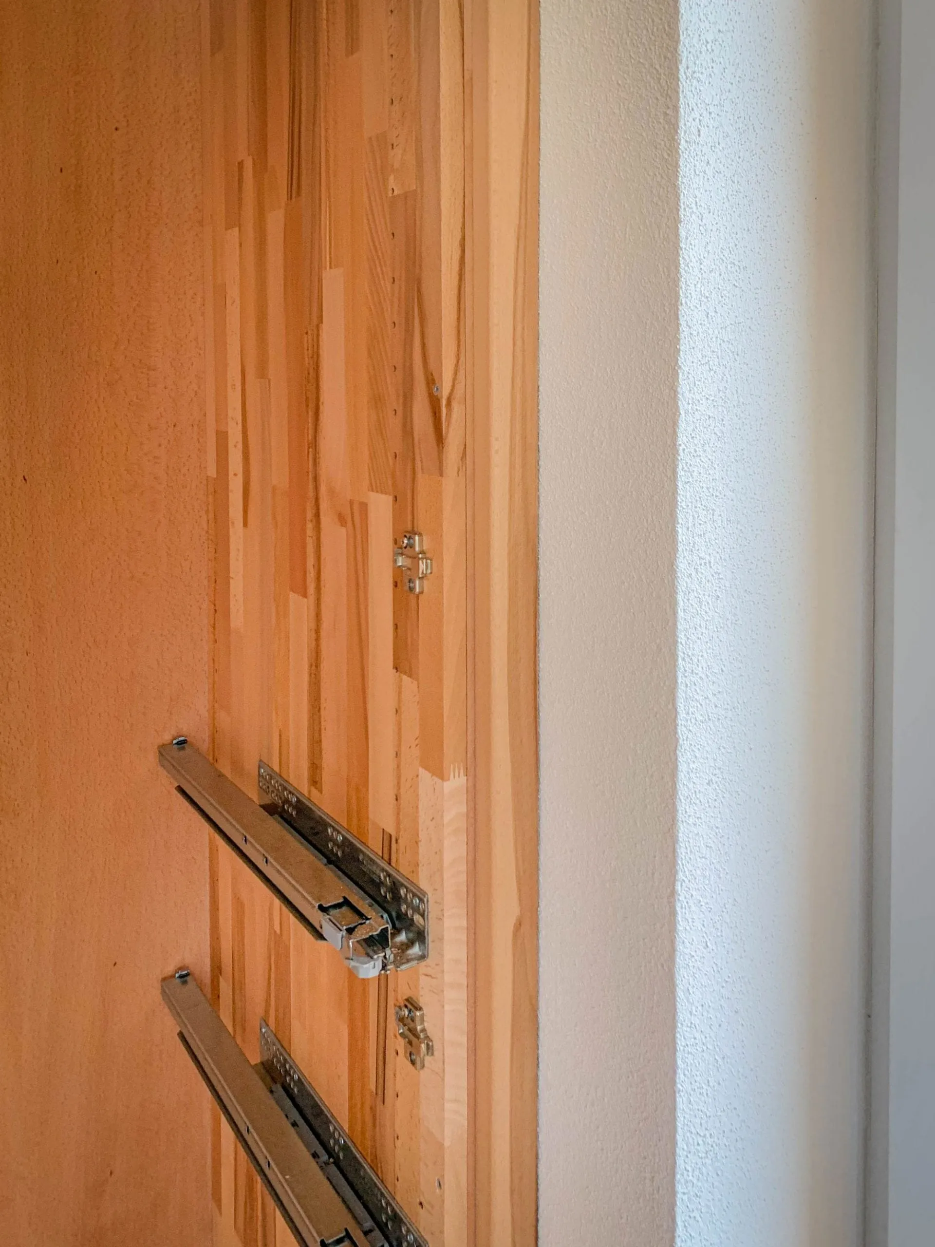 Detailaufnahme einer Massivholz-Korpus-Seitenwange mit montierten Schubladenführungen.