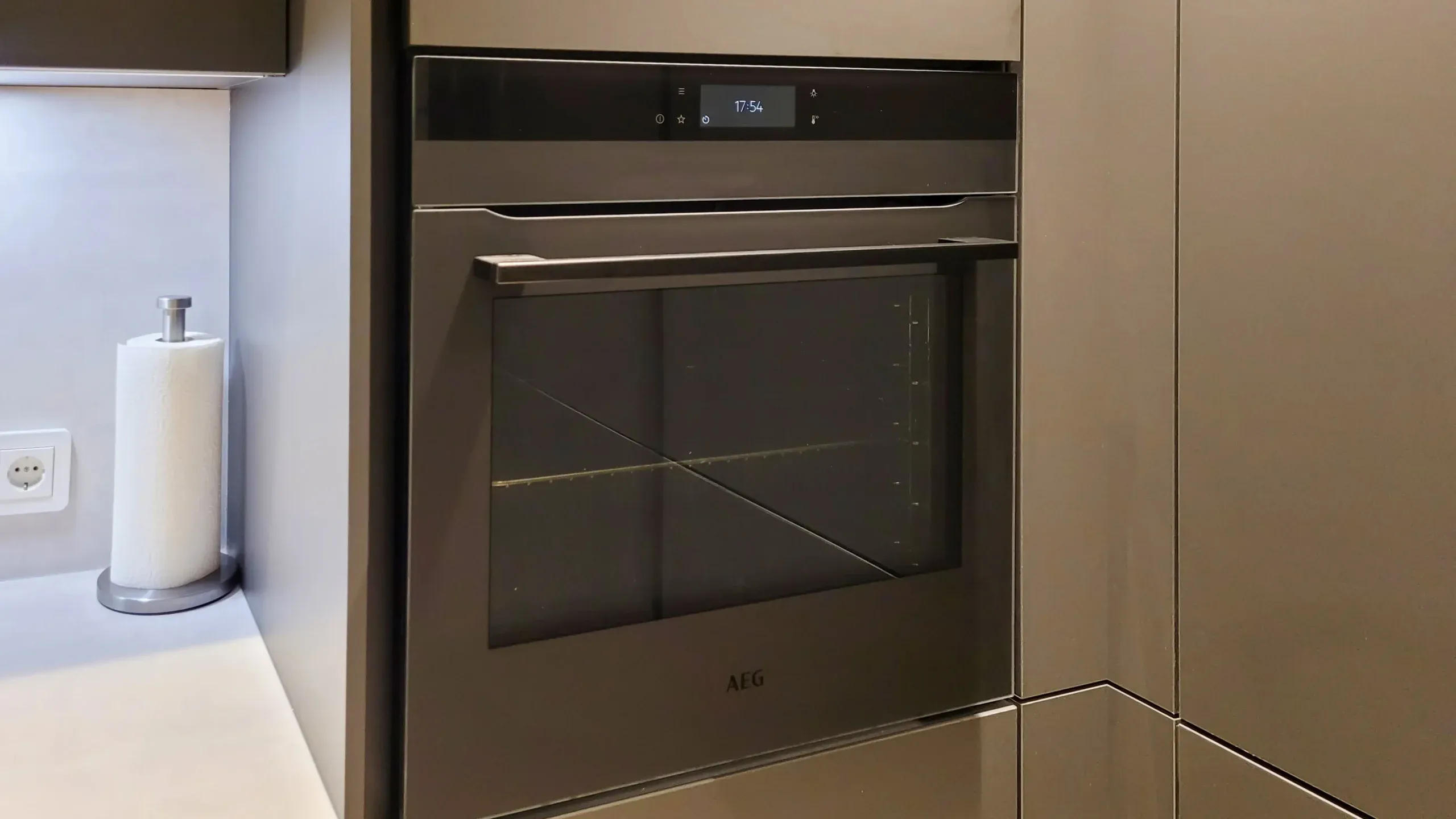Detail Einbau-Backofen im Hochschrank mit Display und Glasfront, eingerahmt in graphitmatte Schrankfronten.