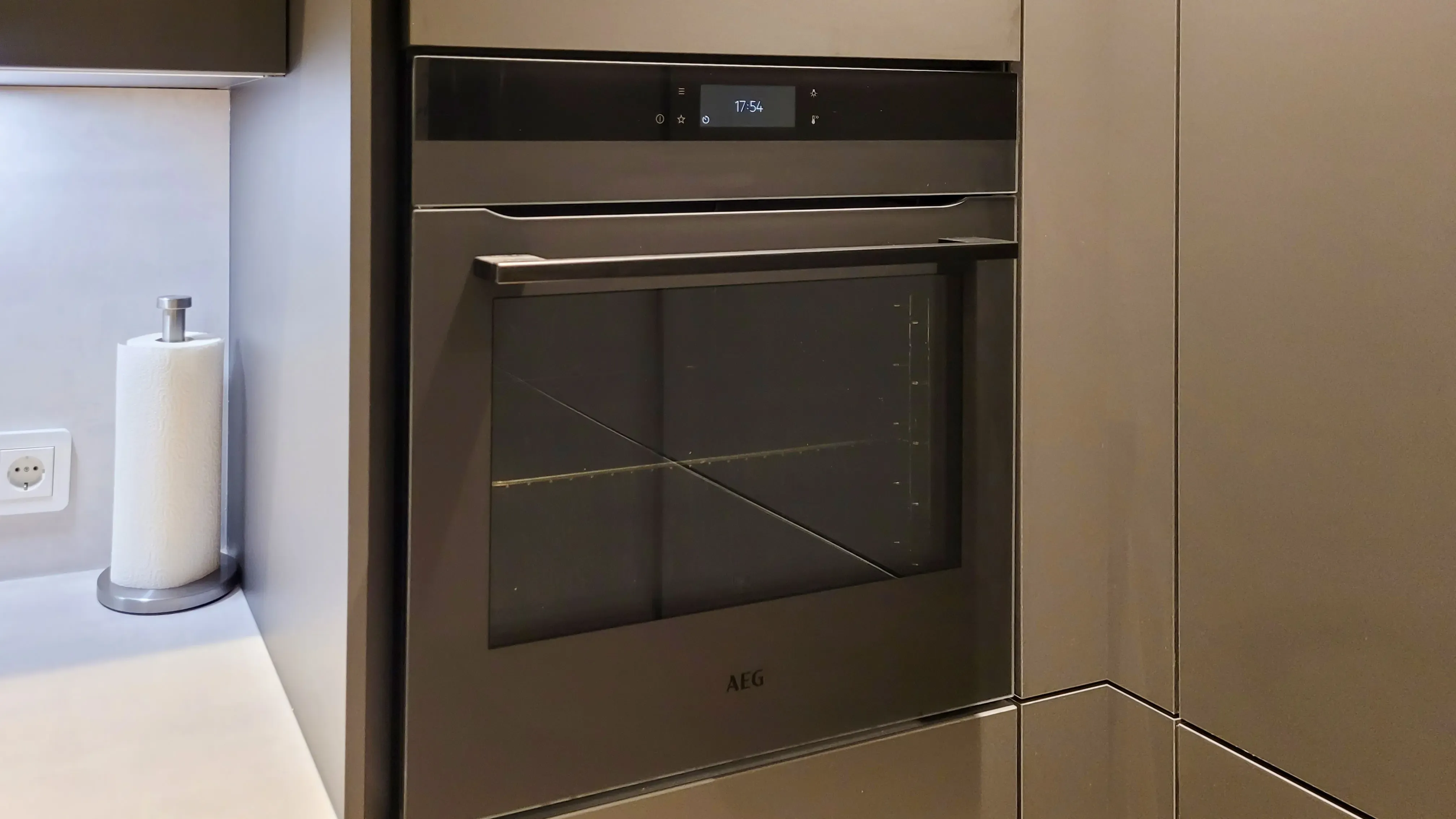 Detail Einbau-Backofen im Hochschrank mit Display und Glasfront, eingerahmt in graphitmatte Schrankfronten.