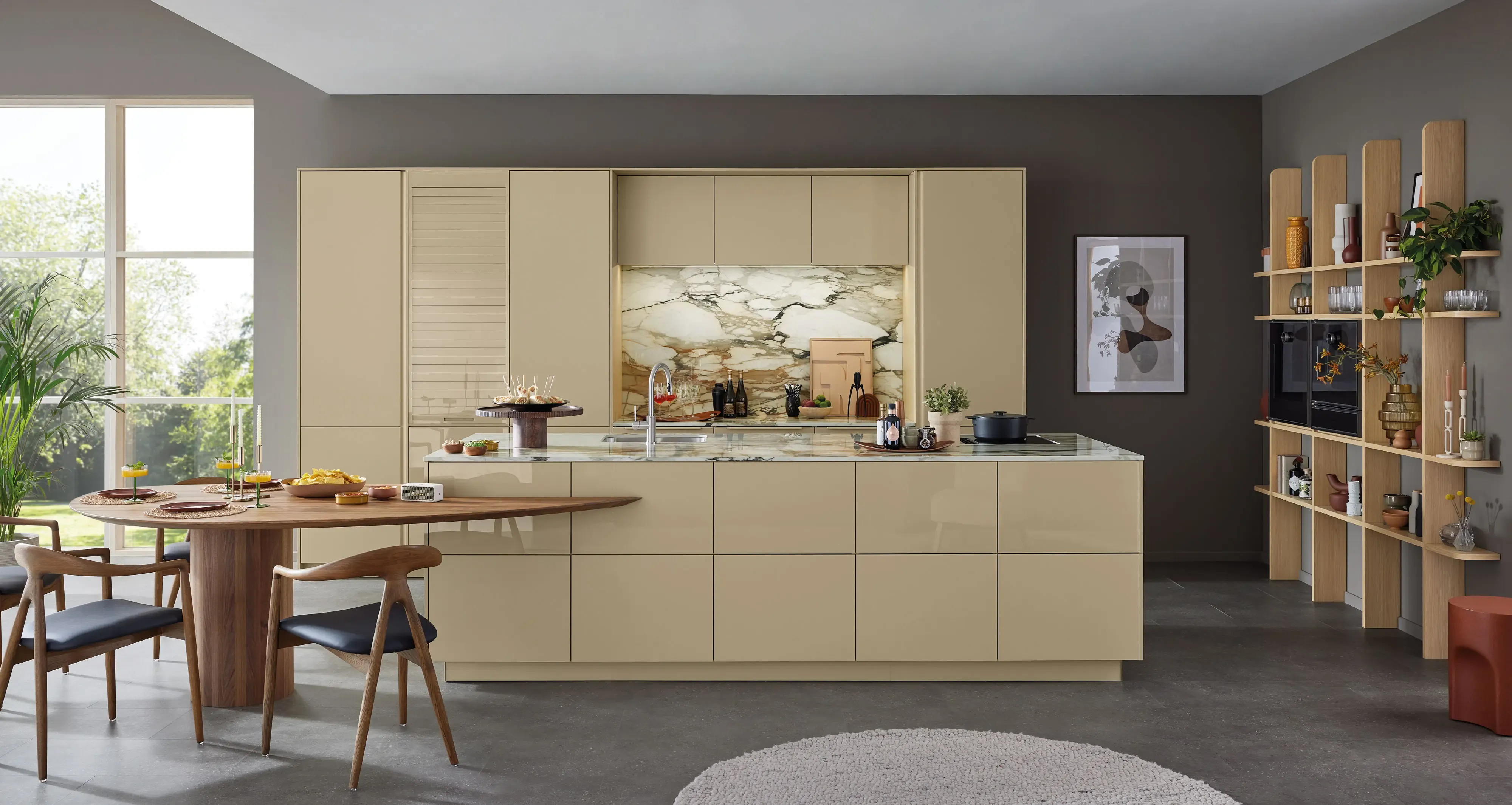 Offene Wohnküche in Sandbeige mit Kocheinsel, Marmor-Rückwand, Essbereich aus Nussbaum und offenem Esche-Regal