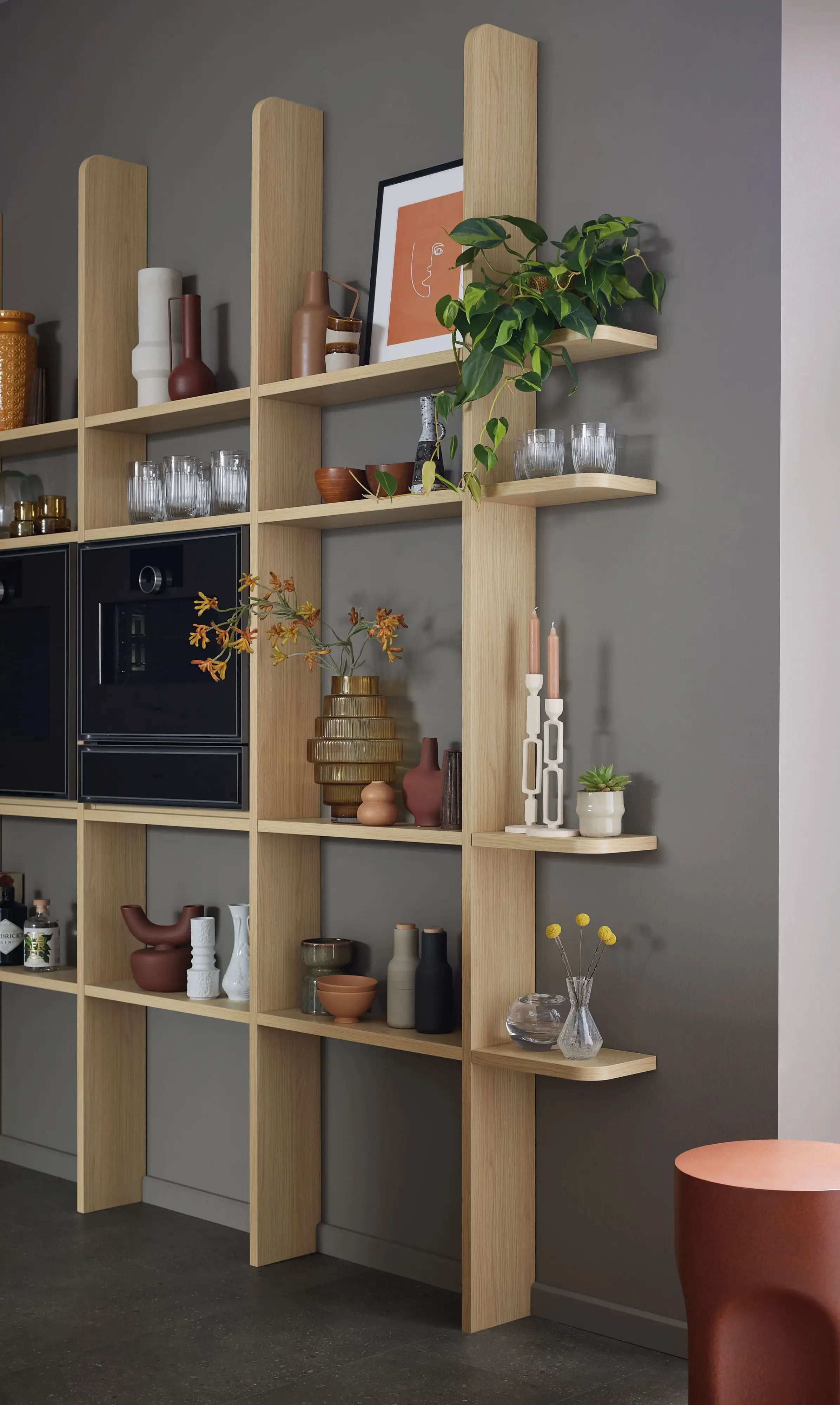 Offenes Holzregal mit Kaffeemaschine, Geschirr und Deko vor anthrazitfarbener Wand