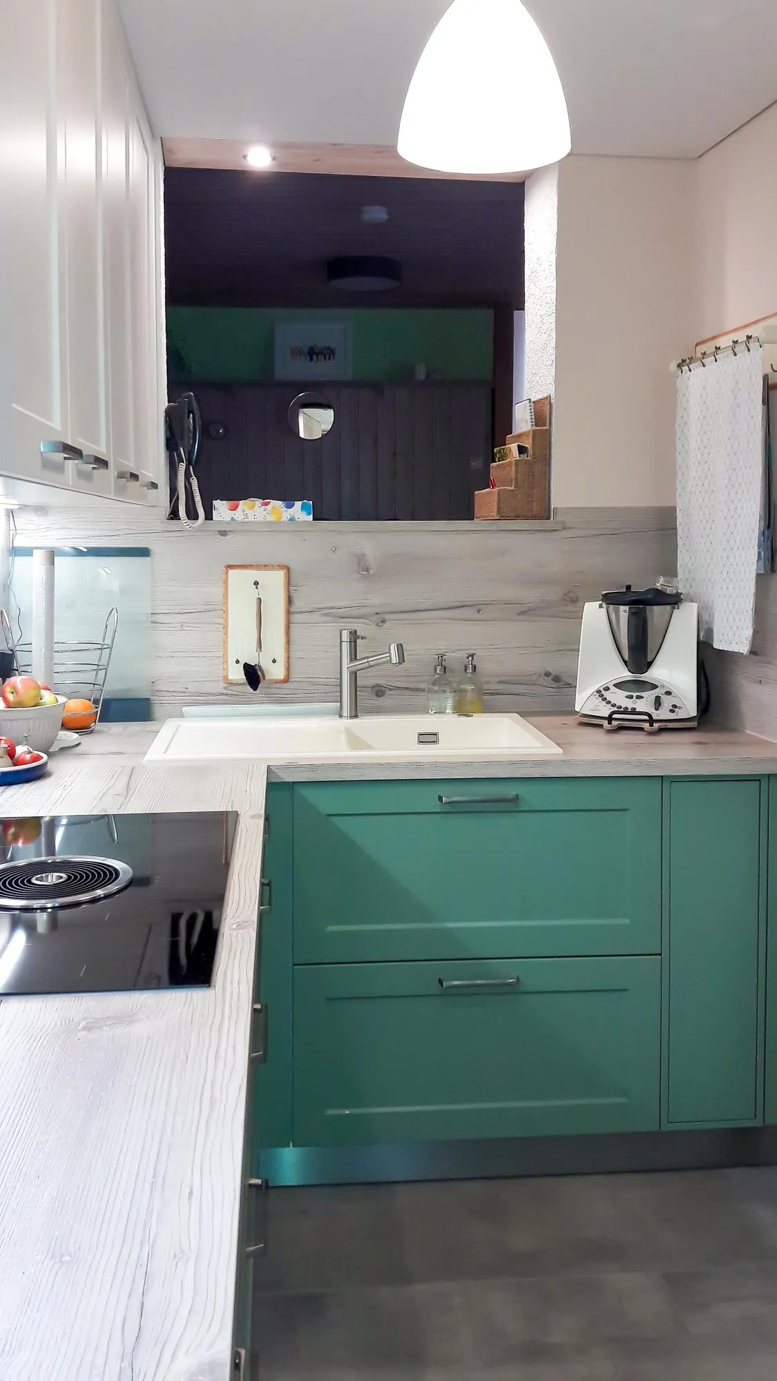 Eckansicht mit eingebautem Backofen, Marmor-Arbeitsplatte, Spüle und Vintage-Holzdielen