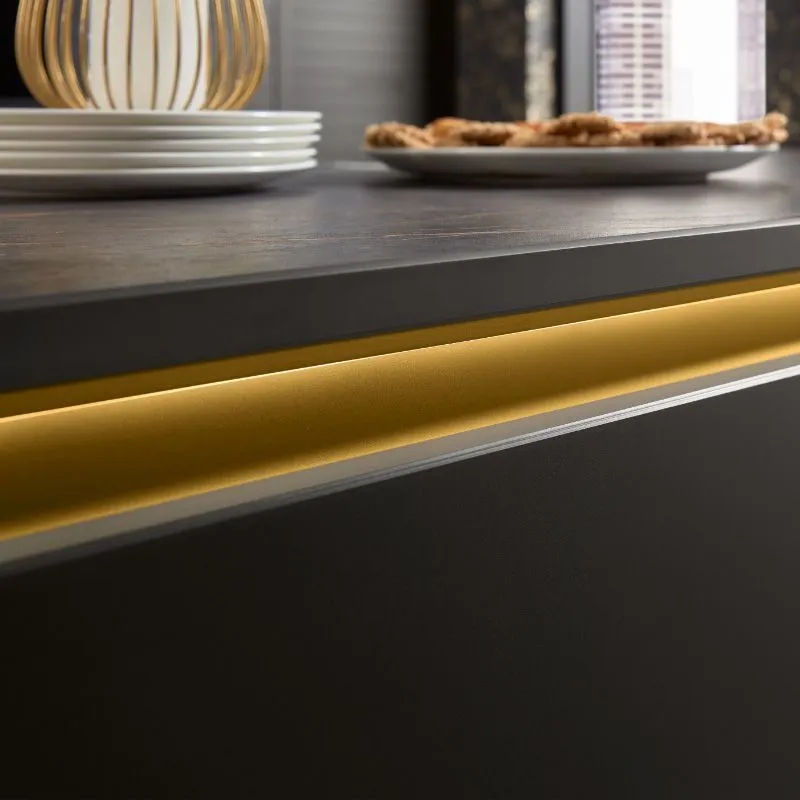 Dunkle Bartheke mit goldenem LED-Sockelband, Tellerstapel und goldener Deko-Vase