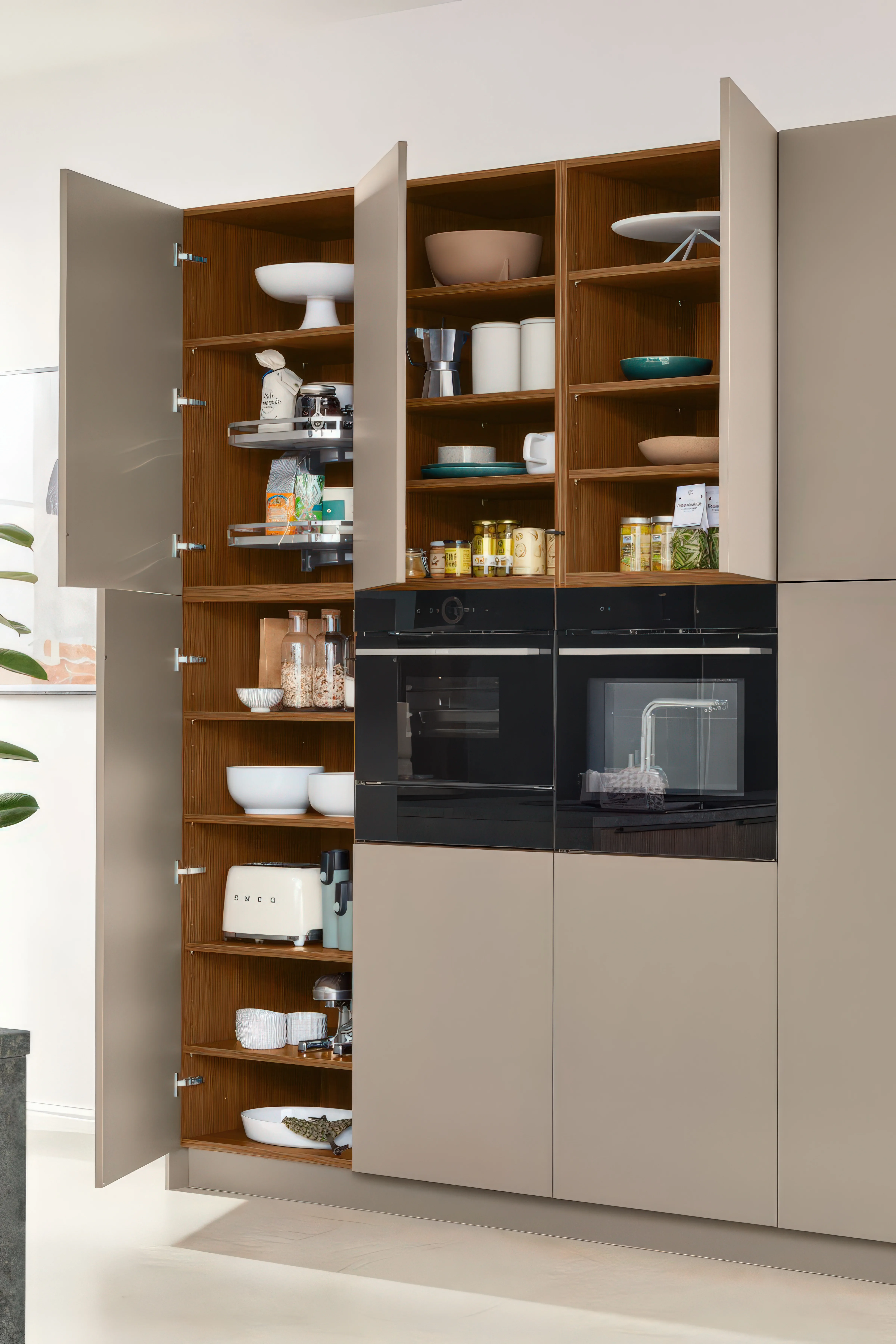 Geöffneter Hochschrank in Taupe mit voll bestücktem Vorrats- und Geschirrregal neben integriertem Backofen