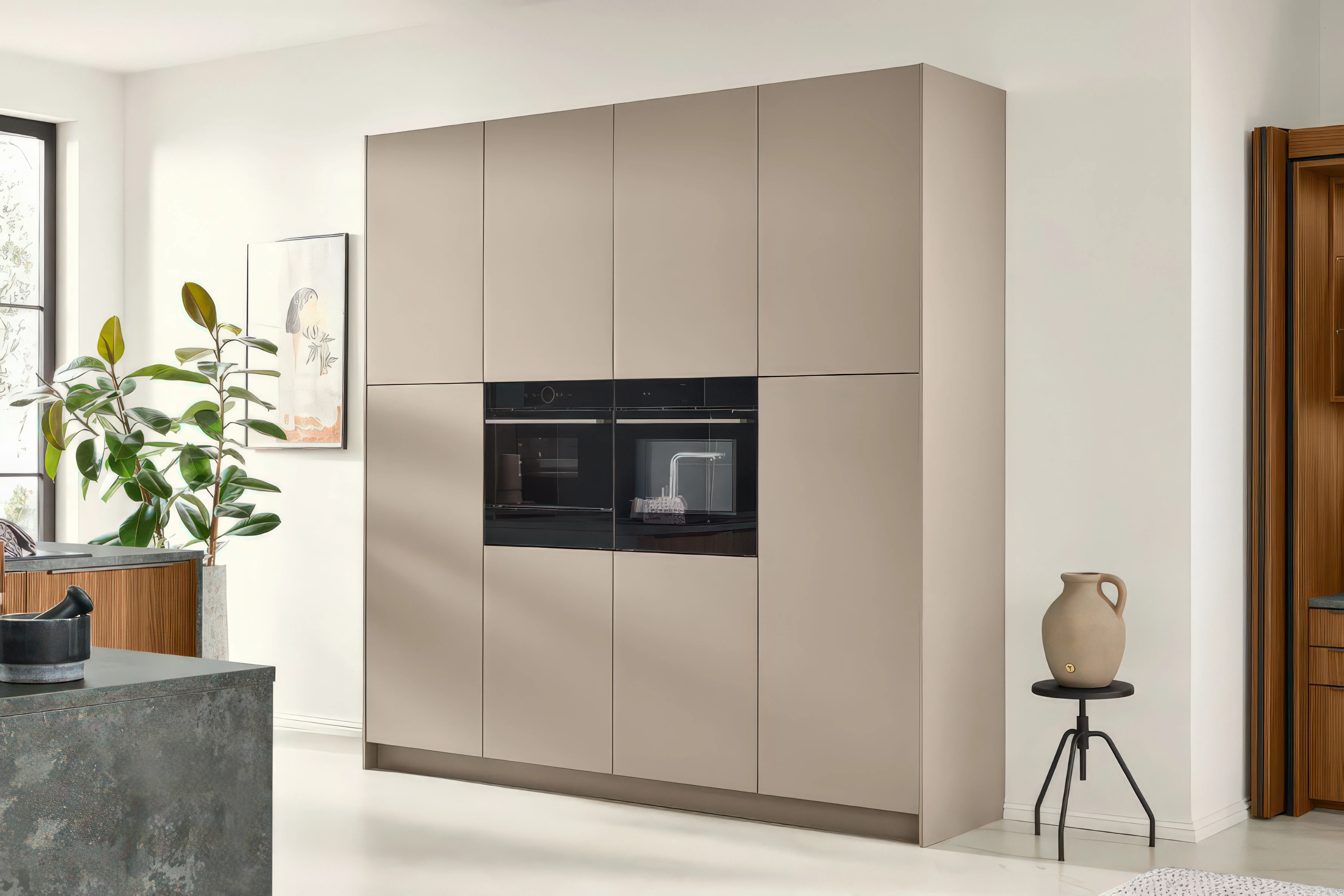 Hochschrankwand in Taupe mit integriertem Backofen, daneben offenes Nussbaum-Regal und Boden-Tonvase