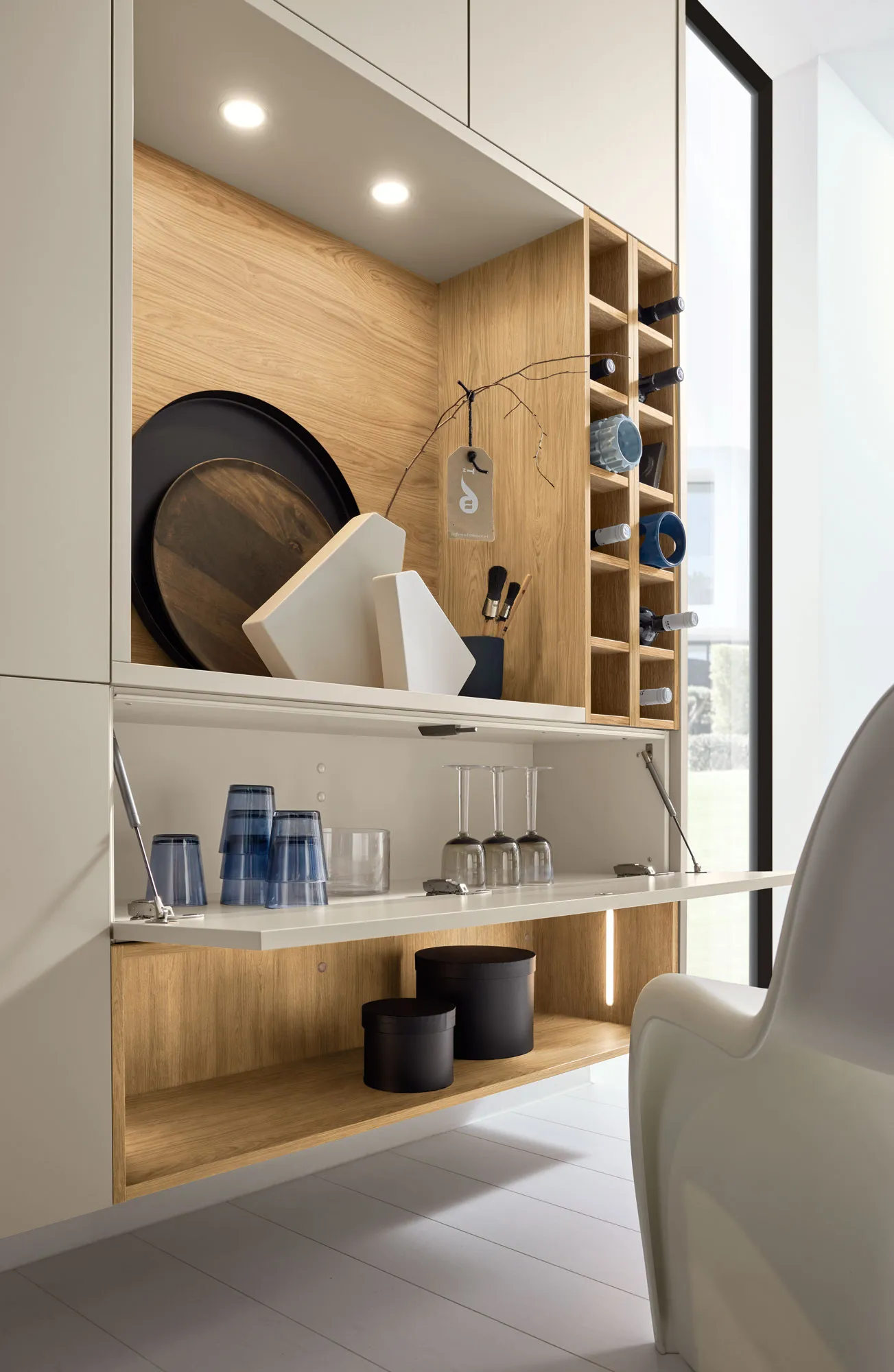 Geöffneter Klappenschrank der Nolte Perfect Plus Wohnwand mit Gläsern und Weinregal